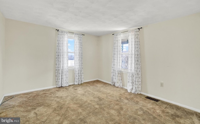 spare room featuring visible vents, carpet floors, and baseboards