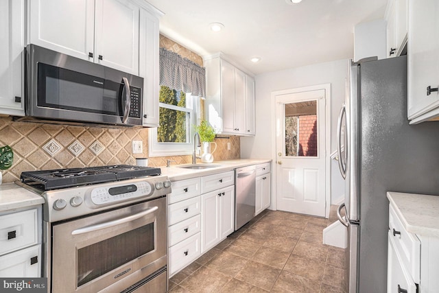 kitchen featuring recessed lighting, a sink, white cabinets, appliances with stainless steel finishes, and backsplash