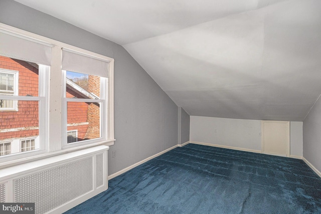 additional living space featuring vaulted ceiling, radiator heating unit, carpet, and baseboards