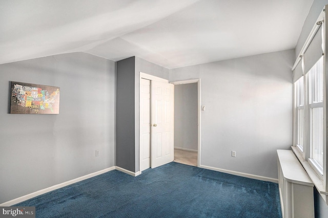 unfurnished bedroom featuring vaulted ceiling, carpet, and baseboards