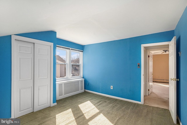 unfurnished bedroom with carpet floors, baseboard heating, radiator heating unit, vaulted ceiling, and baseboards