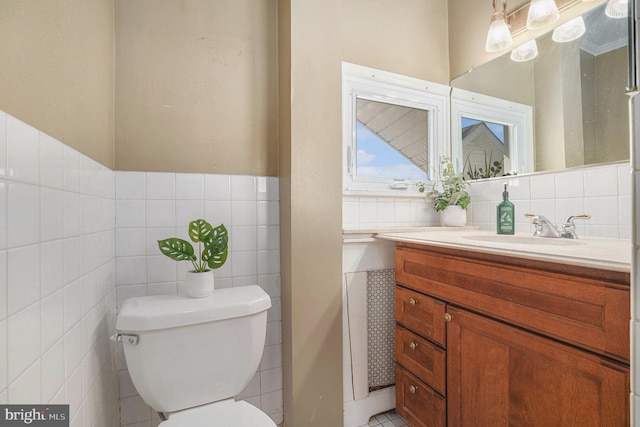 bathroom featuring toilet, a wainscoted wall, tile walls, and vanity