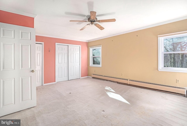 unfurnished bedroom featuring carpet, crown molding, two closets, baseboard heating, and baseboards