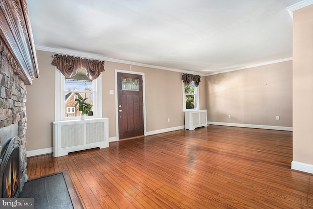 foyer entrance featuring plenty of natural light, radiator heating unit, a fireplace, and hardwood / wood-style flooring