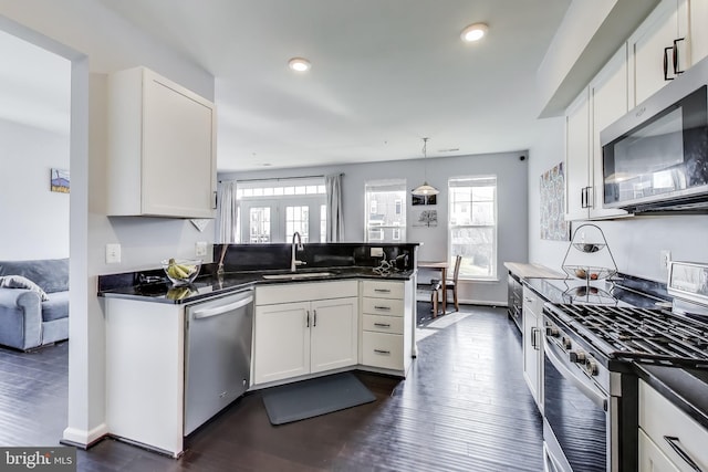 kitchen with appliances with stainless steel finishes, white cabinetry, a peninsula, and a sink