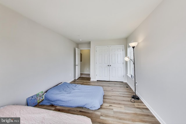 bedroom with wood finished floors, baseboards, and a closet