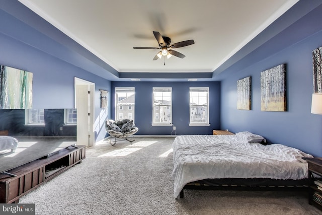 carpeted bedroom featuring a tray ceiling, a ceiling fan, and baseboards