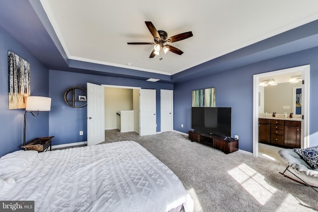 carpeted bedroom featuring a raised ceiling, baseboards, and ensuite bathroom