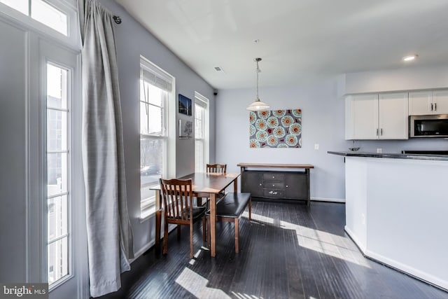 dining space featuring dark wood-style floors, visible vents, and baseboards