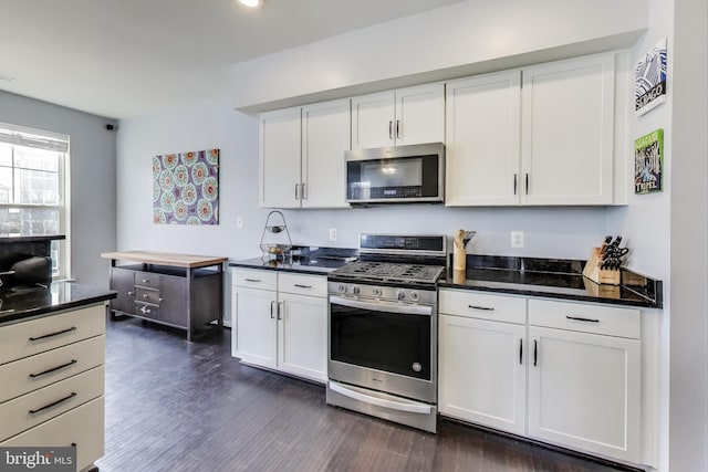 kitchen featuring dark stone counters, appliances with stainless steel finishes, white cabinets, and dark wood-style flooring