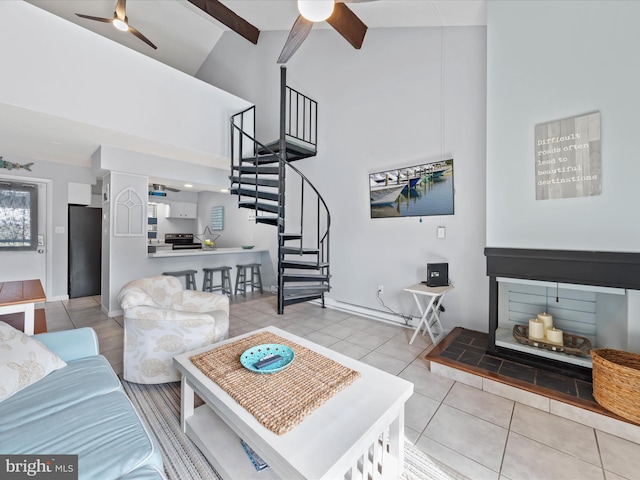 living area featuring tile patterned floors, stairway, high vaulted ceiling, and ceiling fan