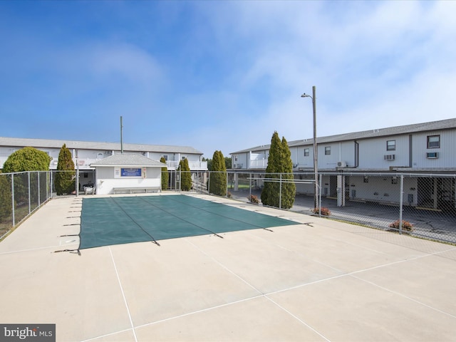 community pool with a patio area and fence