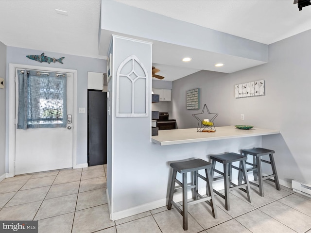 kitchen featuring light tile patterned floors, baseboards, electric range, light countertops, and a kitchen breakfast bar