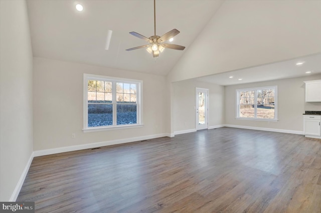 unfurnished living room with high vaulted ceiling, dark wood-style flooring, and baseboards