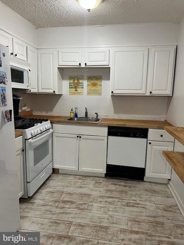 kitchen featuring a sink, white appliances, white cabinets, and butcher block counters