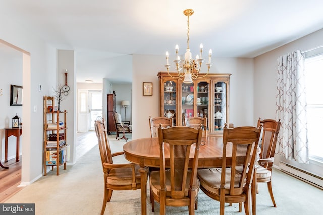dining space featuring a chandelier, light carpet, baseboards, and a baseboard radiator