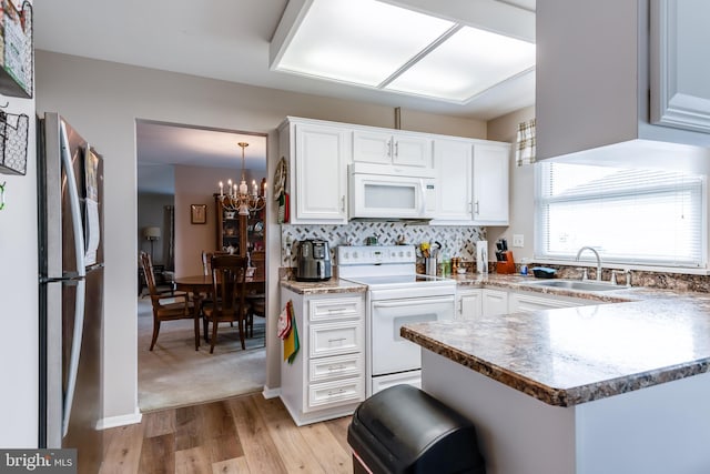 kitchen featuring a notable chandelier, a sink, tasteful backsplash, white appliances, and white cabinets