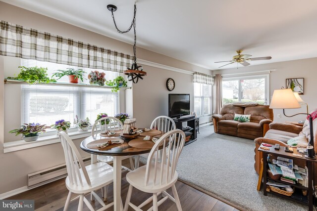 dining area with a baseboard radiator, baseboards, ceiling fan, and wood finished floors