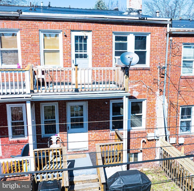 rear view of property featuring a balcony and brick siding