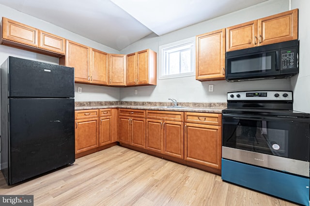 kitchen with light wood-type flooring, brown cabinets, black appliances, a sink, and vaulted ceiling