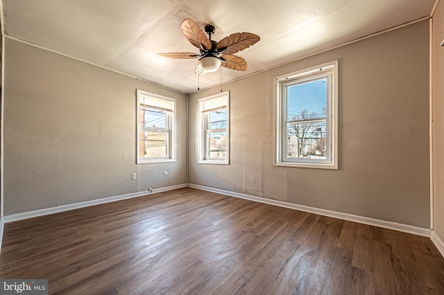 unfurnished room with a wealth of natural light, baseboards, dark wood-type flooring, and ceiling fan