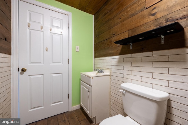 half bath featuring vanity, toilet, and wood finished floors