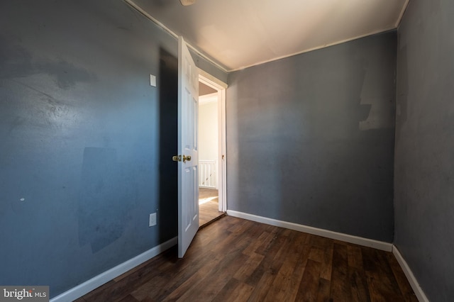 unfurnished bedroom with baseboards, ornamental molding, and dark wood-style flooring