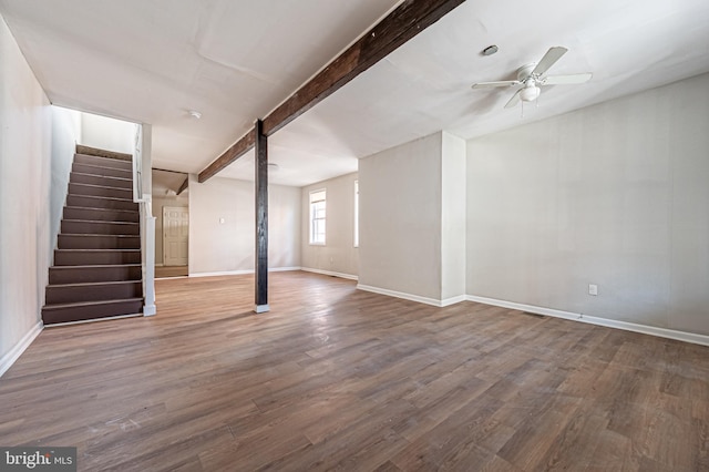 below grade area featuring stairway, baseboards, wood finished floors, and a ceiling fan