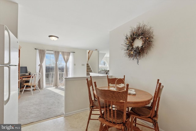 dining area with stairs, light colored carpet, and baseboards