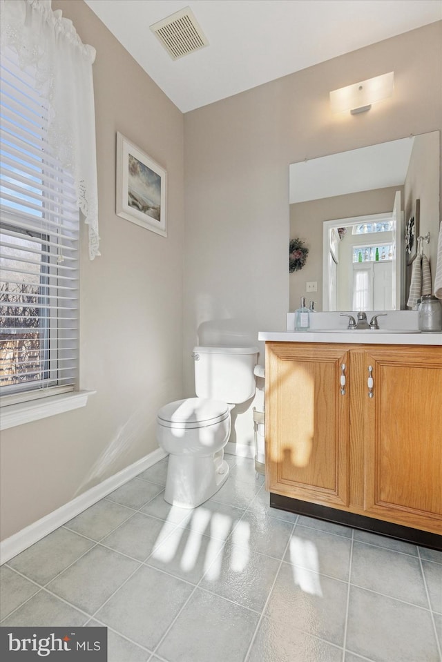 half bathroom featuring tile patterned floors, toilet, baseboards, and visible vents