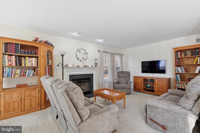 living area with visible vents, light colored carpet, and a glass covered fireplace