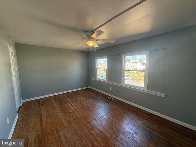 spare room featuring baseboards, visible vents, ceiling fan, and wood finished floors