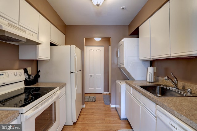 kitchen with under cabinet range hood, stacked washing maching and dryer, white cabinets, white appliances, and a sink