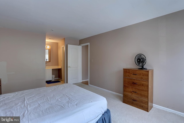 bedroom featuring baseboards, light carpet, and ensuite bath