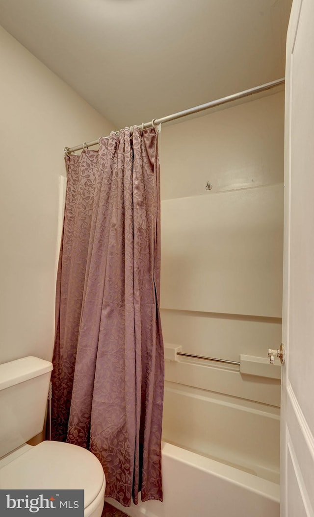 bathroom featuring toilet and shower / tub combo with curtain