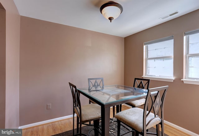 dining area featuring light wood-type flooring, visible vents, and baseboards