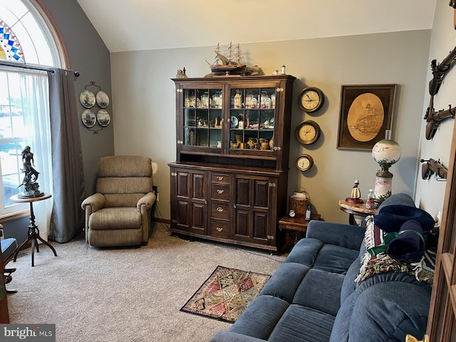 living area with vaulted ceiling and light colored carpet