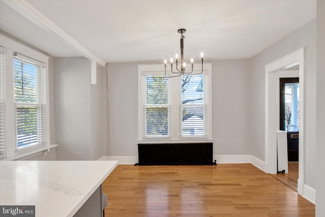 unfurnished dining area with radiator, light wood-style floors, and baseboards