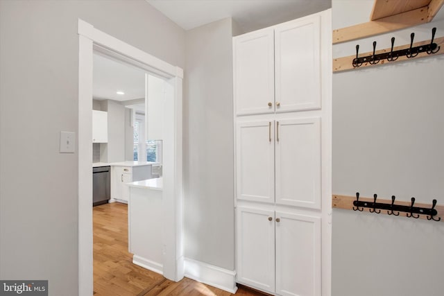 corridor with light wood-type flooring and baseboards