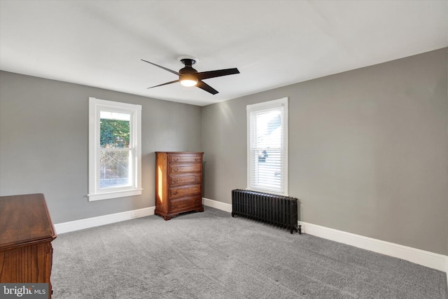 unfurnished bedroom featuring carpet flooring, baseboards, ceiling fan, and radiator heating unit