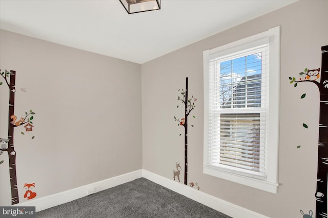 empty room with baseboards and dark colored carpet