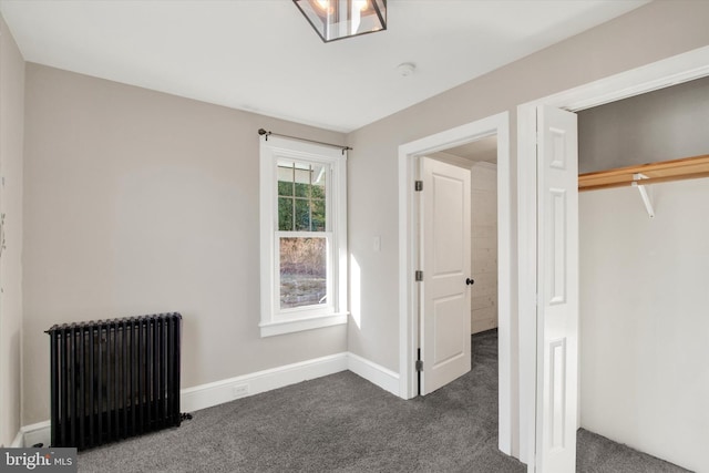 unfurnished bedroom featuring dark colored carpet, a closet, baseboards, and radiator