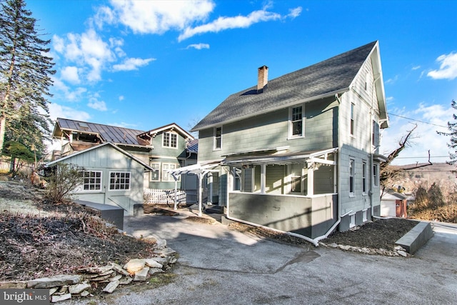 back of property featuring driveway and a chimney