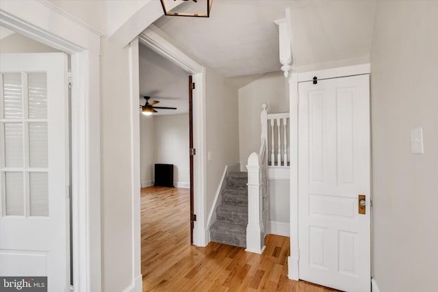 corridor with stairway, light wood-type flooring, and baseboards