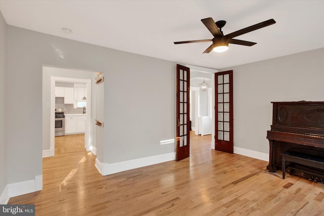 living room with french doors, baseboards, ceiling fan, and light wood finished floors