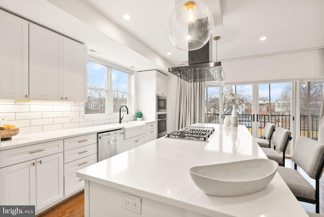 kitchen with a sink, a center island, appliances with stainless steel finishes, white cabinets, and decorative backsplash