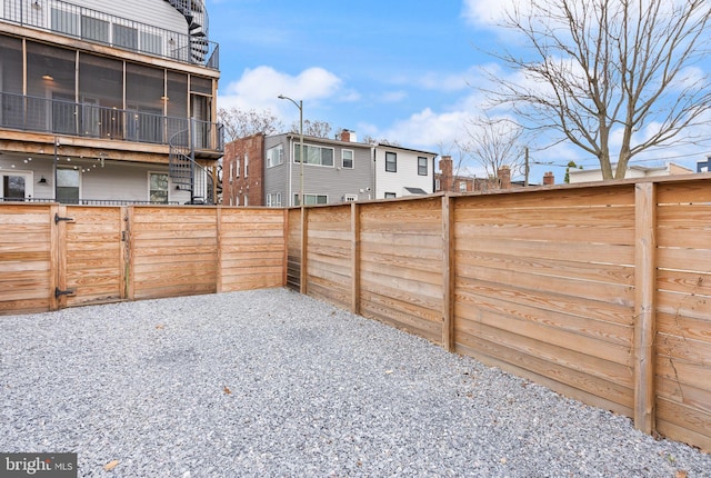 view of yard featuring a gate, fence, and a sunroom