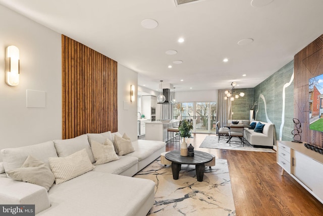 living room featuring recessed lighting, an inviting chandelier, and wood finished floors