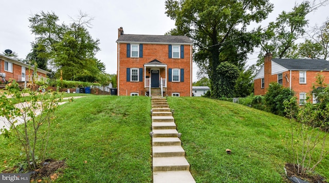 view of front of property with a front yard, brick siding, and a chimney