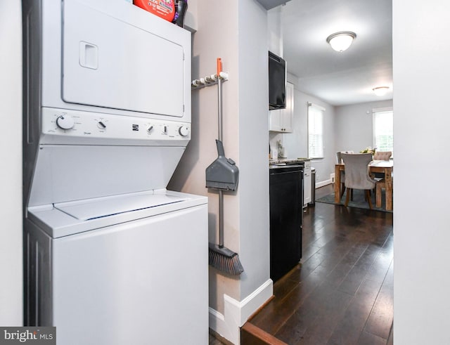 clothes washing area with stacked washer and dryer, baseboards, laundry area, and dark wood-style flooring